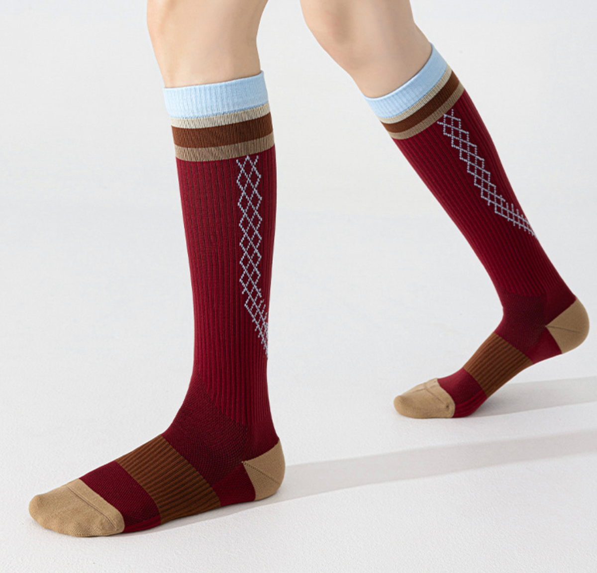 Volleyball knee high socks in red athletic knit, featuring a light blue stripe and cushioned heel. Worn on legs for sport.