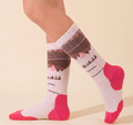 Walking boot socks in pink and brown, featuring a mountain and forest motif with a pink heel. Worn on a foot to show the cushioned fit.