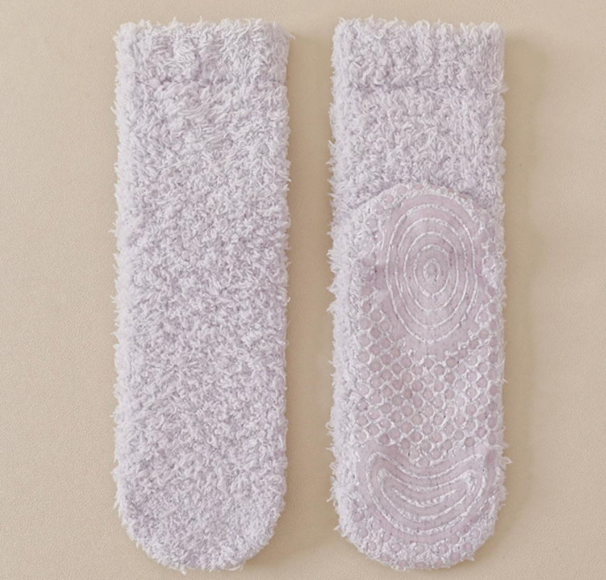 Warm socks for chilblains in lilac plush, featuring a non-slip gripped underside. Laid flat as a cozy pair for warmth and comfort.