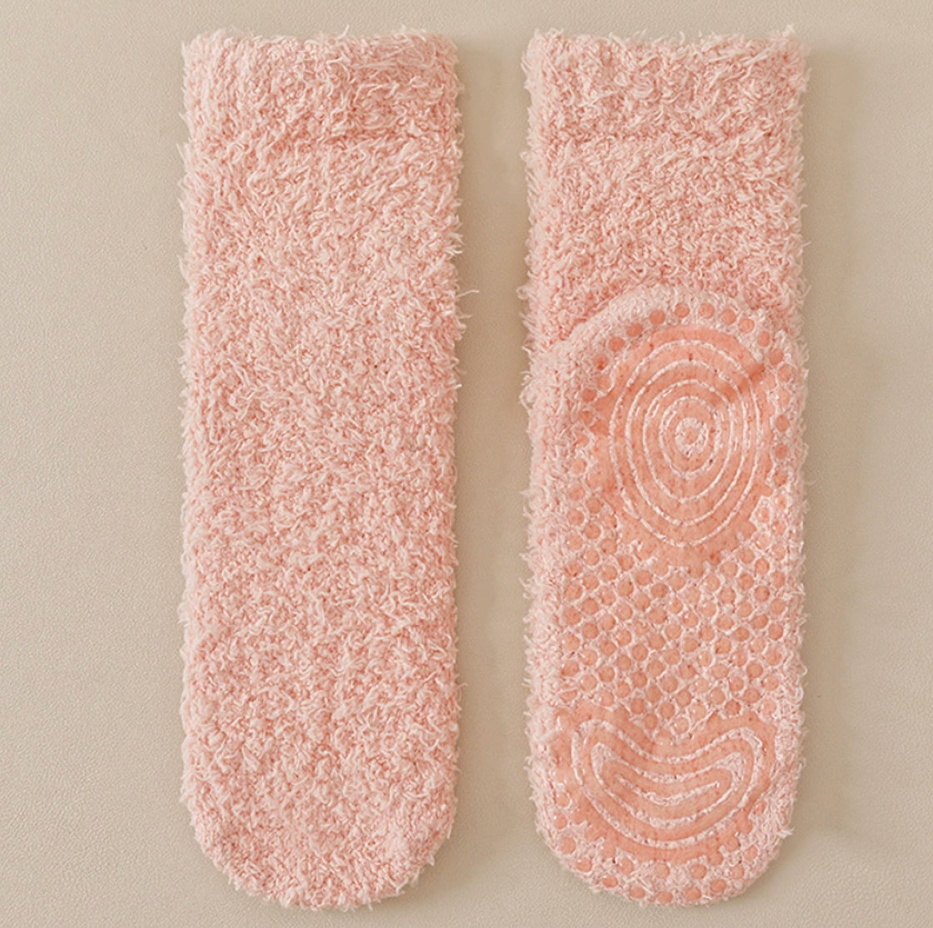 Warm socks for chilblains in soft peach fleece, featuring a swirl-pattern non-slip sole. Displayed as a pair to show the grip detail.