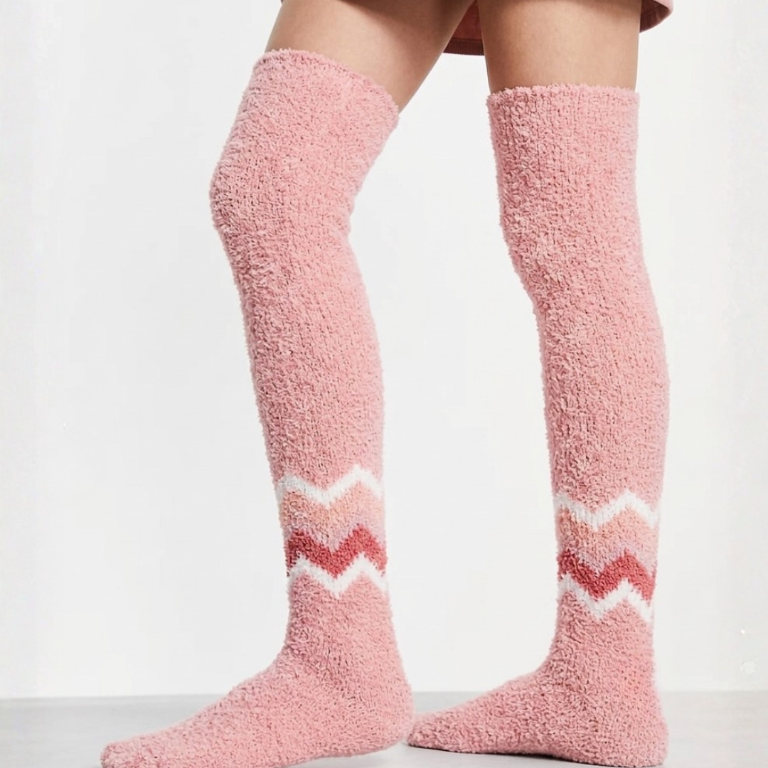 Warm socks for cold feet in pink plush knit, featuring a white and pink chevron stripe. Worn on legs in a cozy indoor setting.