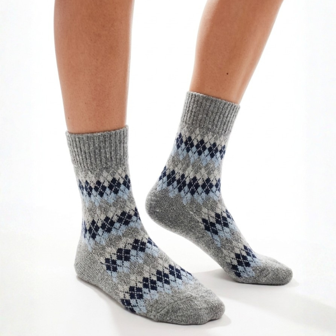 Warm winter socks in grey wool, featuring a navy Fair Isle diamond pattern. Worn on feet for a cozy layered look.