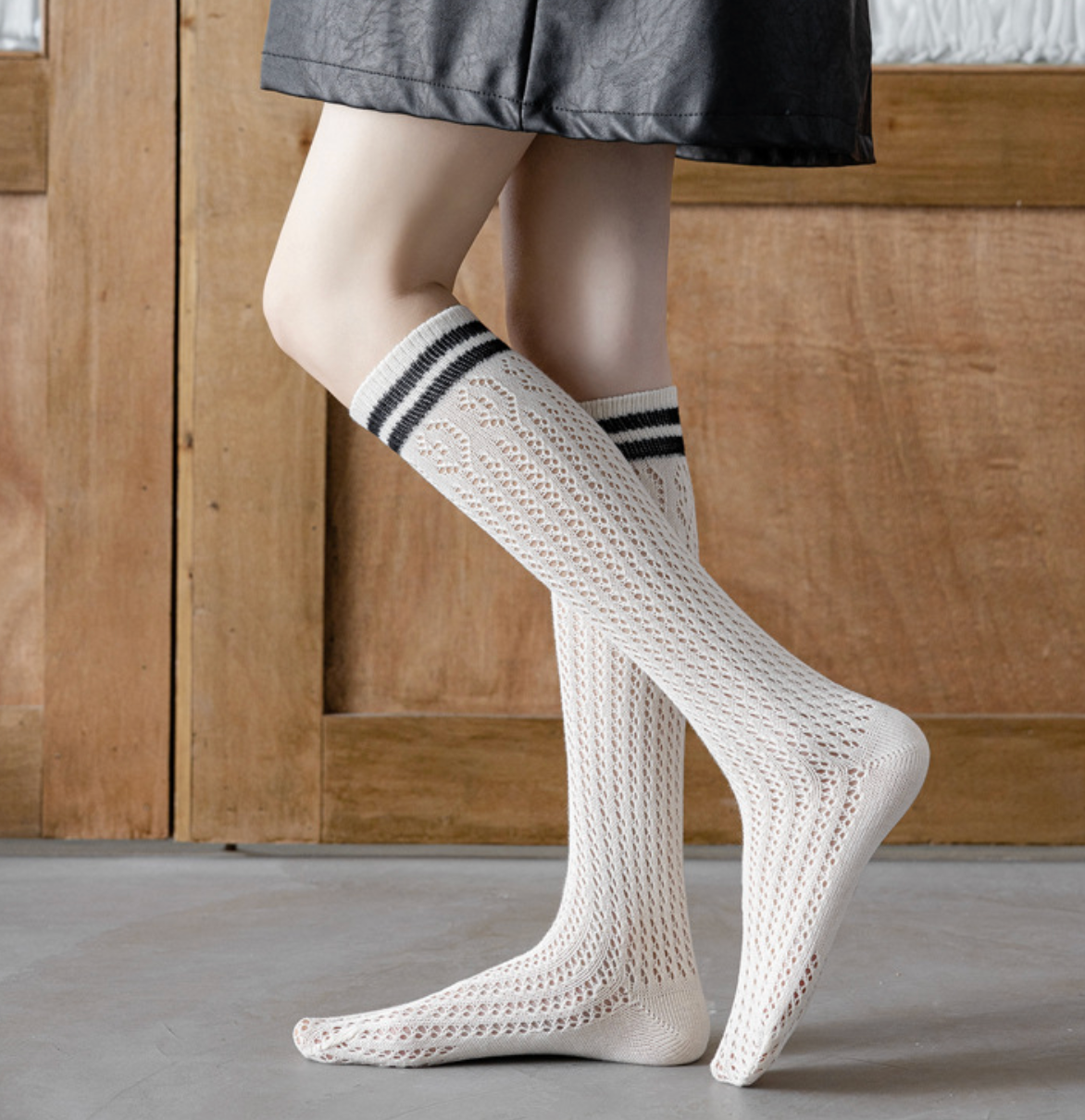 White knee socks with black stripe accents, featuring a ribbed knee-high leg. Worn on legs against a neutral backdrop.