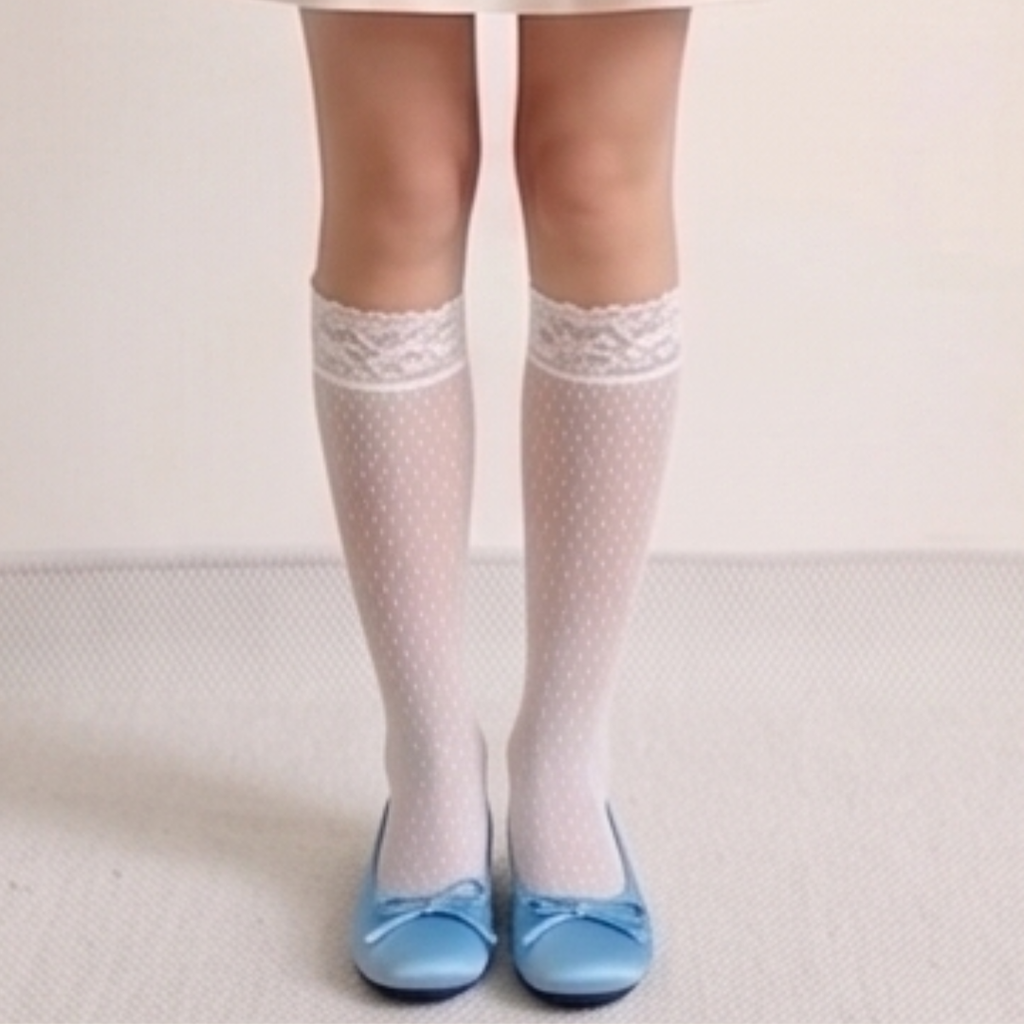 White lace knee high socks in white ribbed knit, featuring a delicate lace top. Worn standing with blue flats.