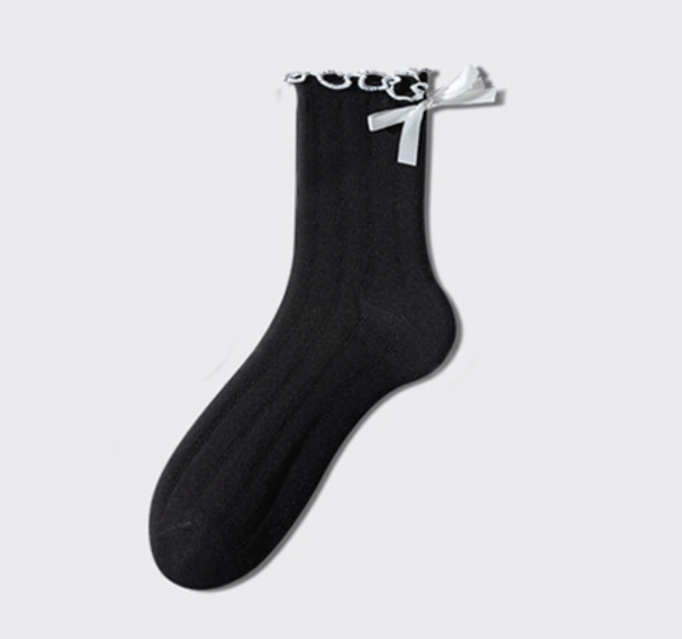 White ruffle socks shown in the black colorway with a white bow, single sock laid flat.