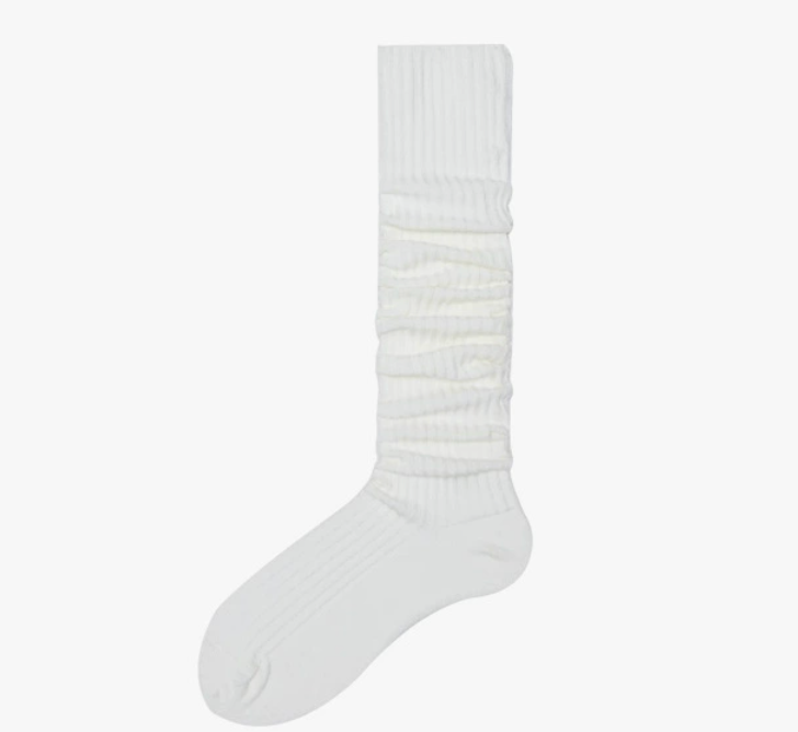 White slouch socks in ivory knit, featuring a long bunched leg. Worn on one foot to show the drapey slouch.