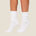 White slouch socks in soft knit, featuring a scrunched slouchy leg. Worn on the legs in a casual look.