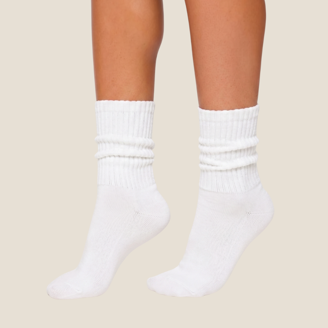 White slouch socks in soft knit, featuring a scrunched slouchy leg. Worn on the legs in a casual look.