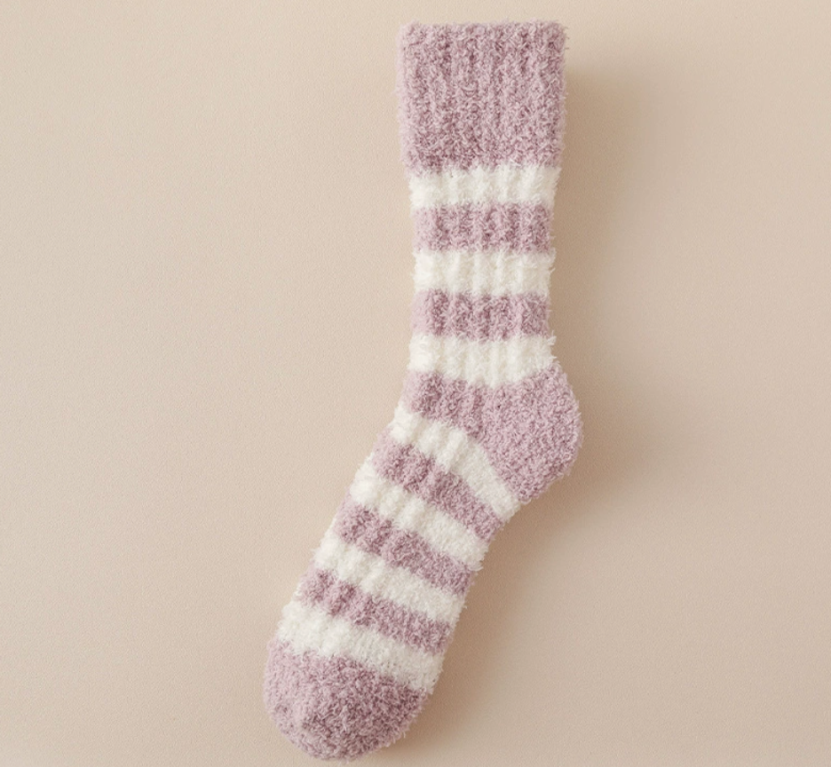 Women's bed socks in mauve and cream fleece, featuring soft horizontal stripes. Shown as a single flat-lay on a warm surface.