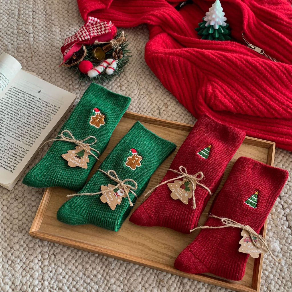 Women's Christmas socks, embroidered red and green pairs tied with bows and arranged in a gift box.