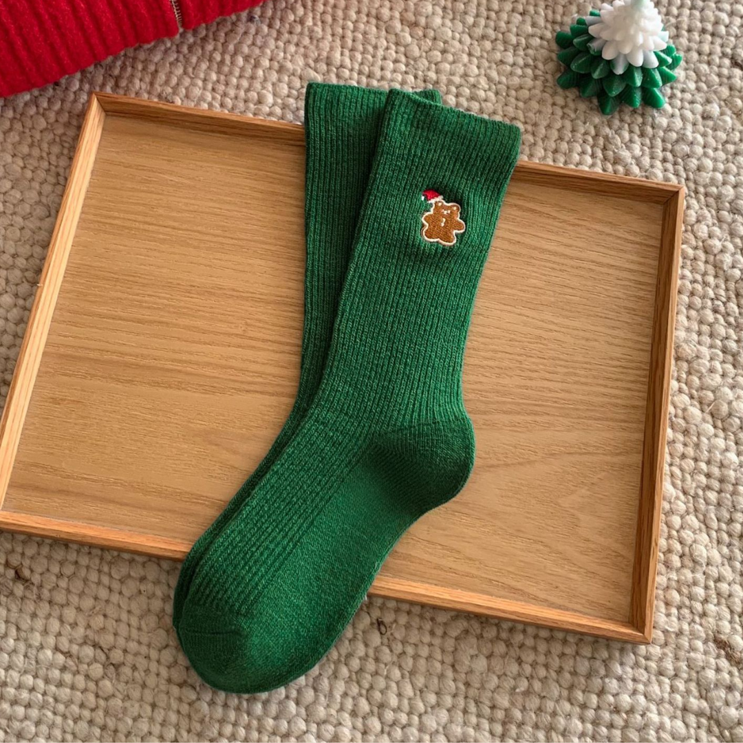 Women's Christmas socks in green with an embroidered detail, single sock shown on a wooden tray.