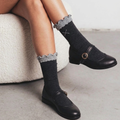 Women's cute socks in gray with a lace ruffle cuff, styled with black Mary Jane shoes, side view.