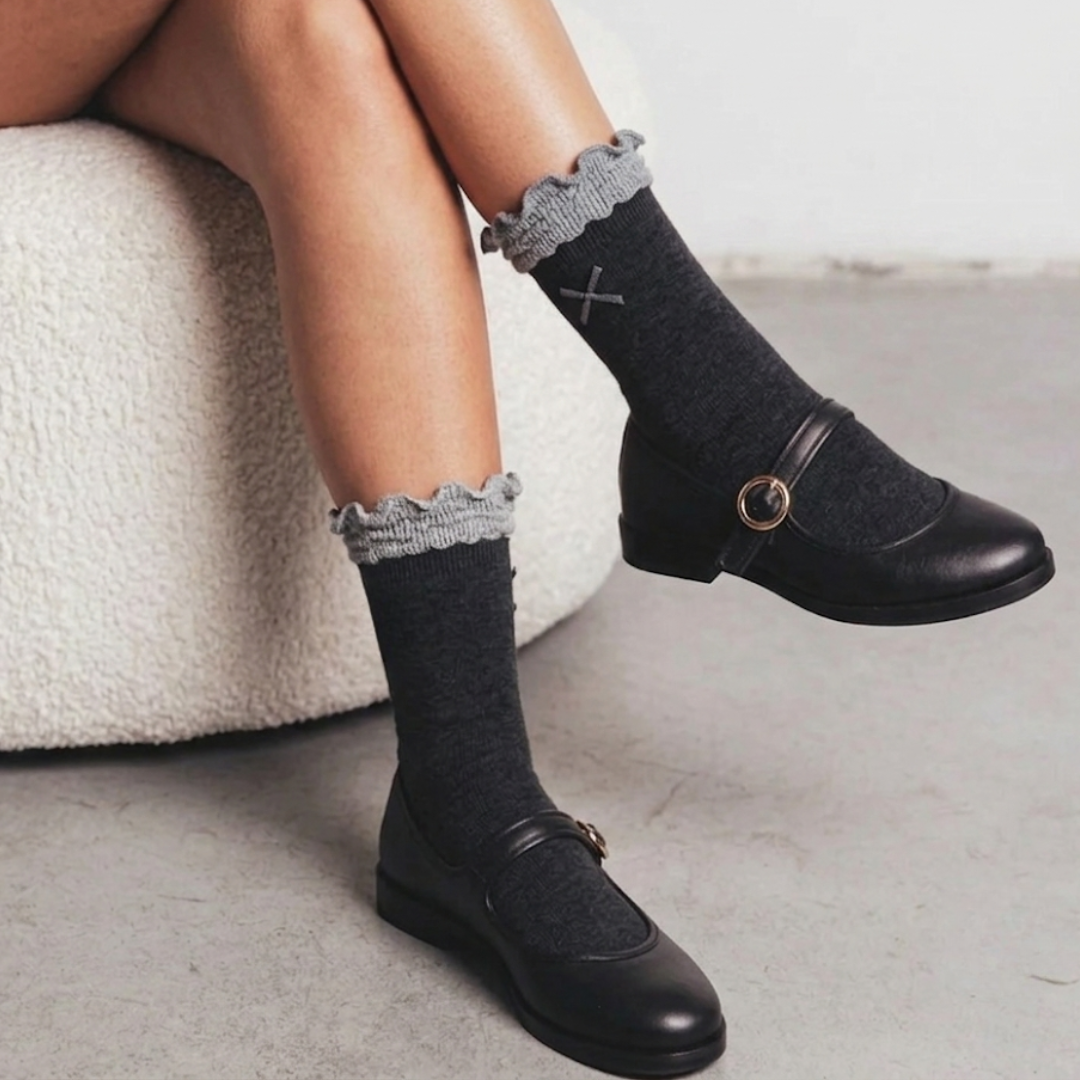 Women's cute socks in gray with a lace ruffle cuff, styled with black Mary Jane shoes, side view.