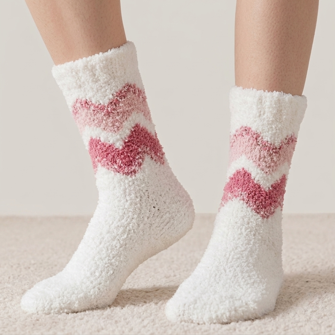 Women's fleece socks in white plush fleece with a pink chevron stripe, worn on the feet.