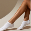 Women's no show socks in white, featuring an invisible low-cut design. Worn on feet in a bright studio setting.
