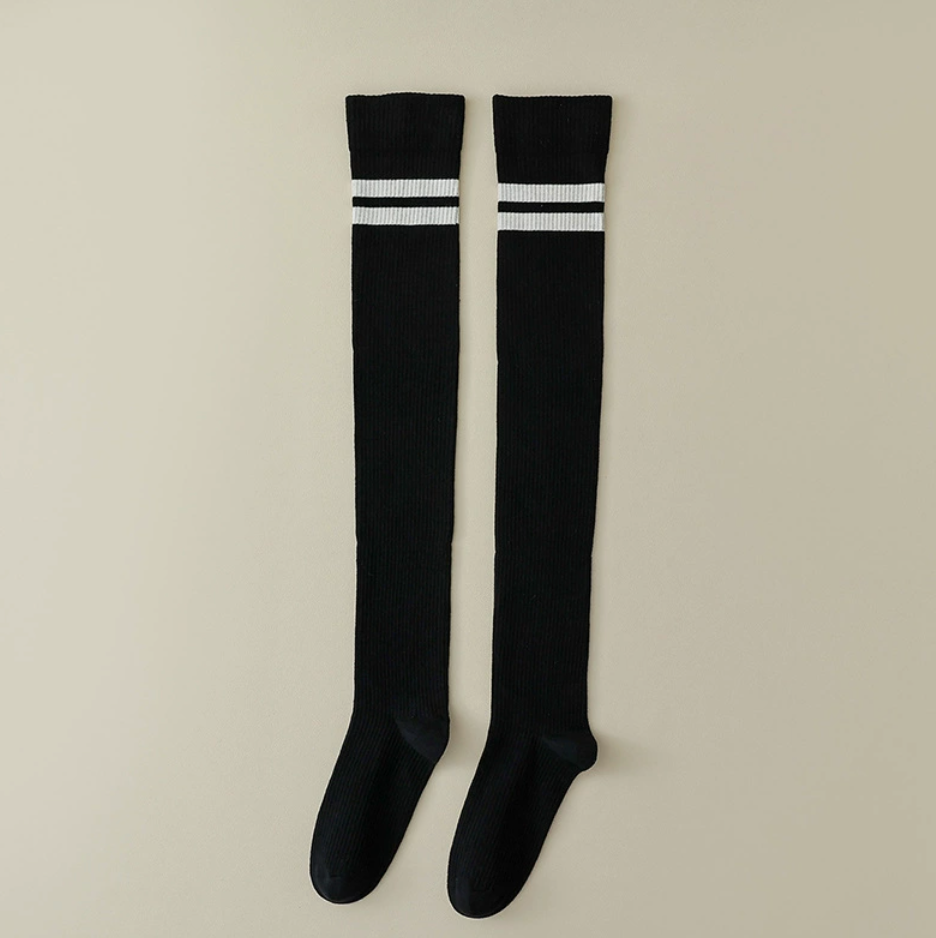 Women's over the knee socks in black with white stripe bands, featuring a thigh-high leg. Shown as an upright flat-lay pair.