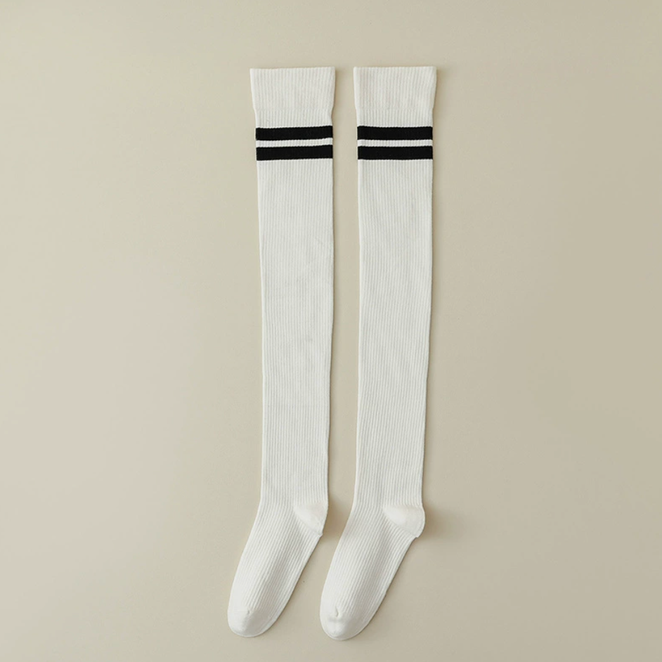 Women's over the knee socks in cream with black stripes, featuring a sporty cuff. Displayed flat as a pair on a light backdrop.