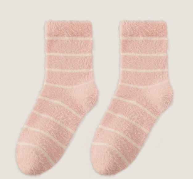 Women's sleep socks in blush pink and cream plush, featuring cozy striped detailing. Shown flat as a pair to highlight the fuzzy knit.