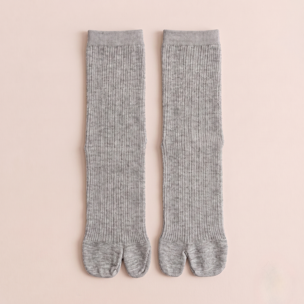 Women's tabi socks in grey, featuring a split-toe design and ribbed body. Shown as a flat-lay pair on a light backdrop.