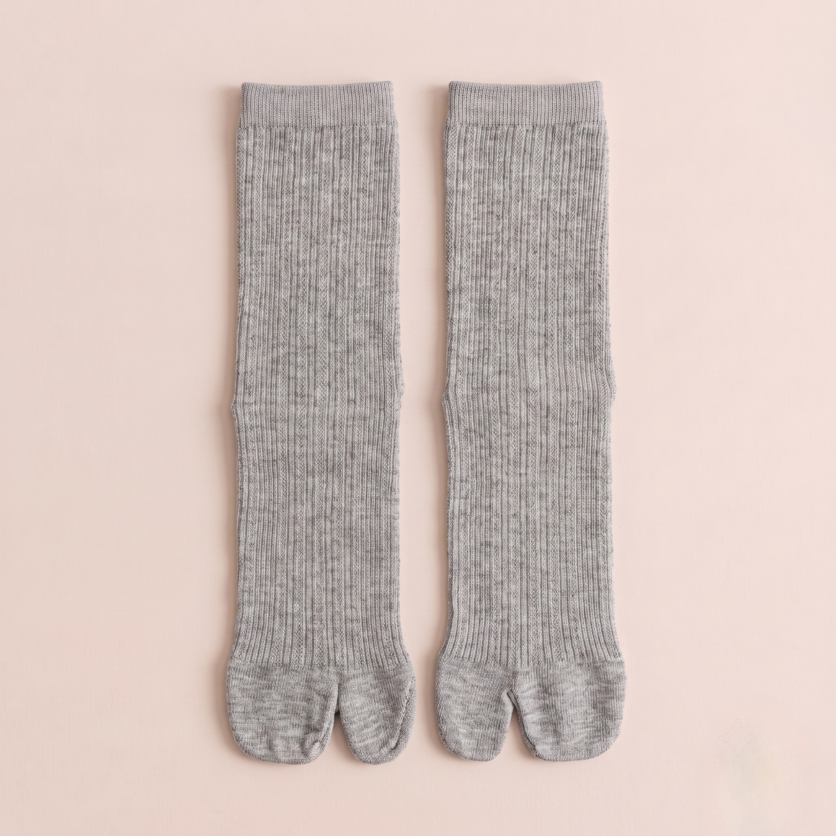 Women's tabi socks in grey, featuring a split-toe design and ribbed body. Shown as a flat-lay pair on a light backdrop.