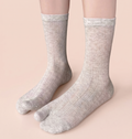Women's tabi socks in oatmeal, featuring a split-toe ribbed knit. Worn on feet to show the divided toe.