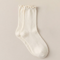Women's wool boot socks in cream, featuring a ribbed knit with a frilled scalloped cuff. Displayed flat on a soft surface.