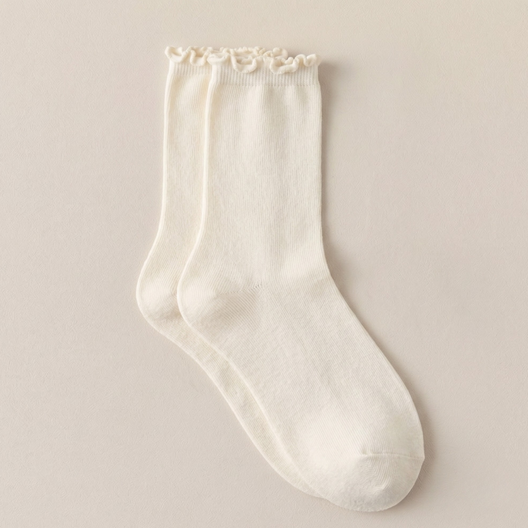 Women's wool boot socks in cream, featuring a ribbed knit with a frilled scalloped cuff. Displayed flat on a soft surface.
