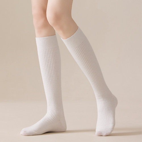 Women's wool knee socks in cream ribbed knit, featuring a snug knee-high fit. Worn on bent legs against a soft backdrop.