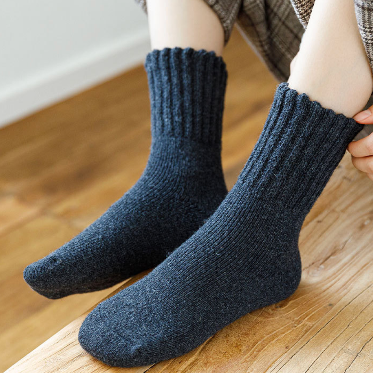 Wool thick socks in navy blue, featuring a dense ribbed knit. Worn on foot over a wooden floor.