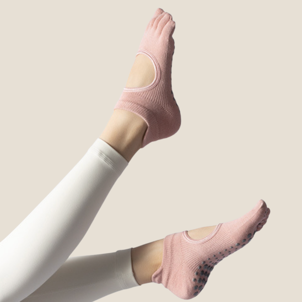 Yoga toe socks in pink knit, featuring an open-toe backless design with grip sole. Worn on crossed legs during practice.